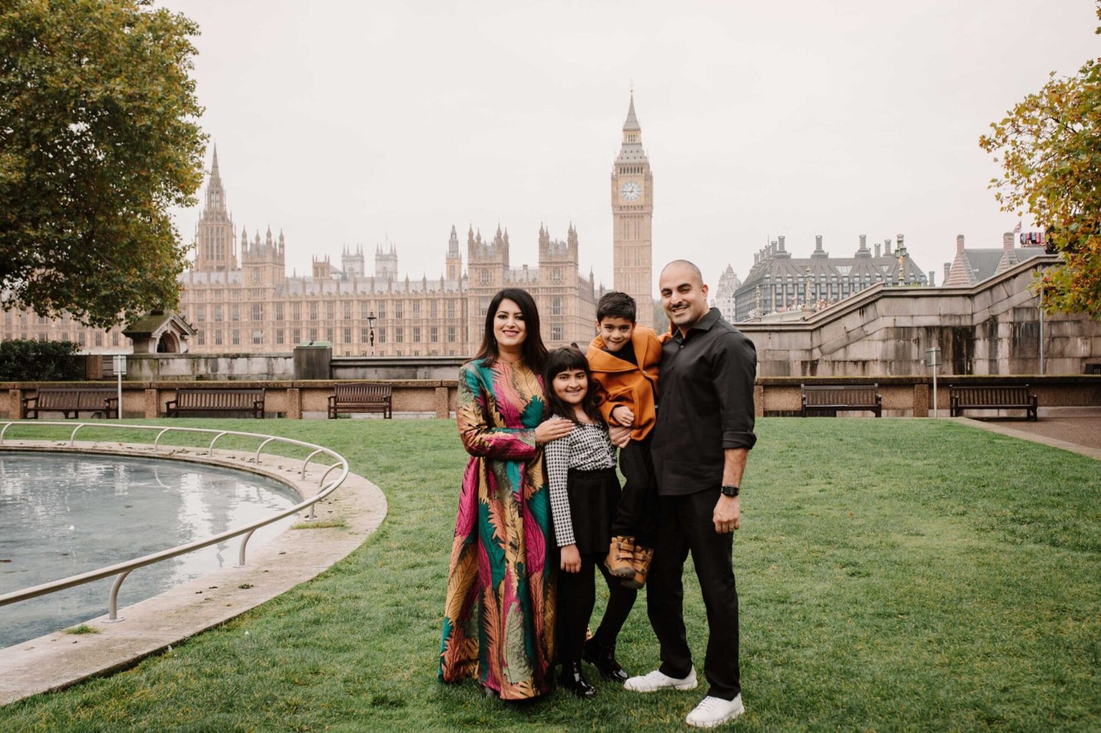 Family standing together in a garden with Big Ben and the Houses of Parliament behind them