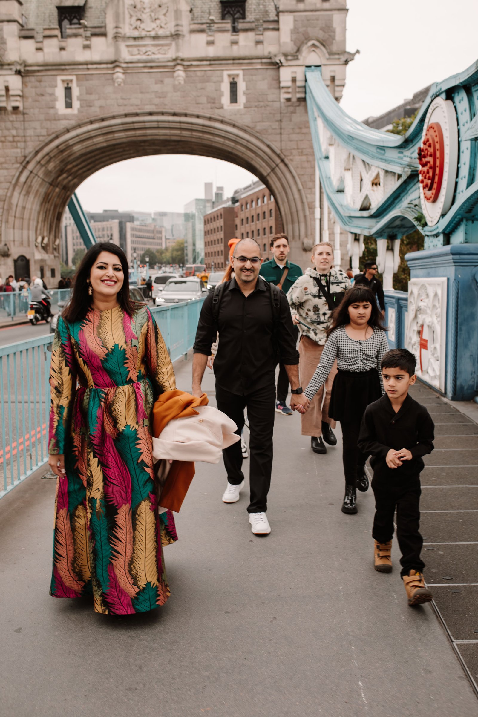 Family from the USA walking together beneath the arches of Tower Bridge