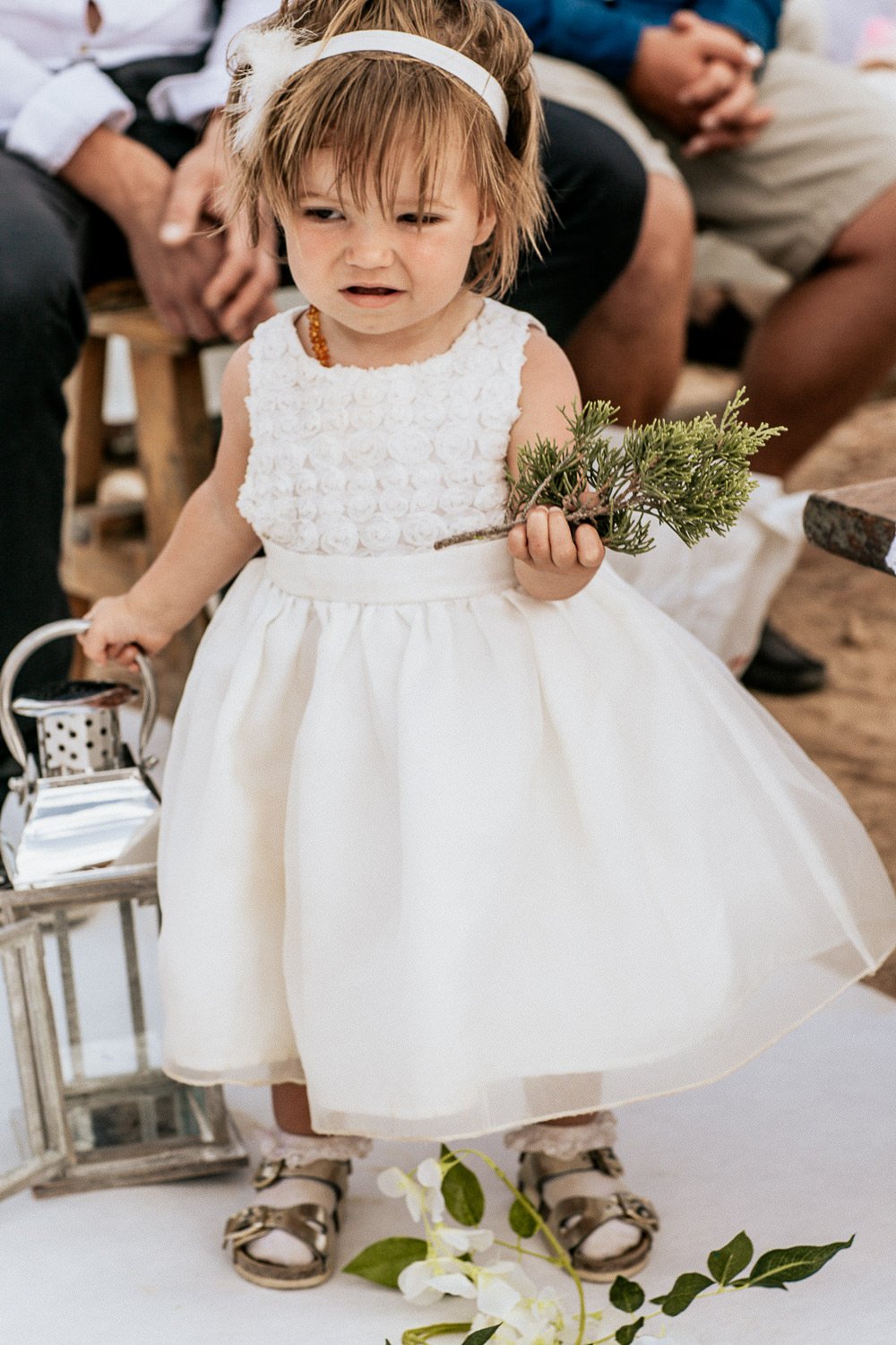 A young wedding guest in a white dress watching the ceremony